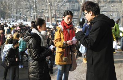 昨日，中国传媒大学考场外，一工作人员（右一）正在叫考生入场。