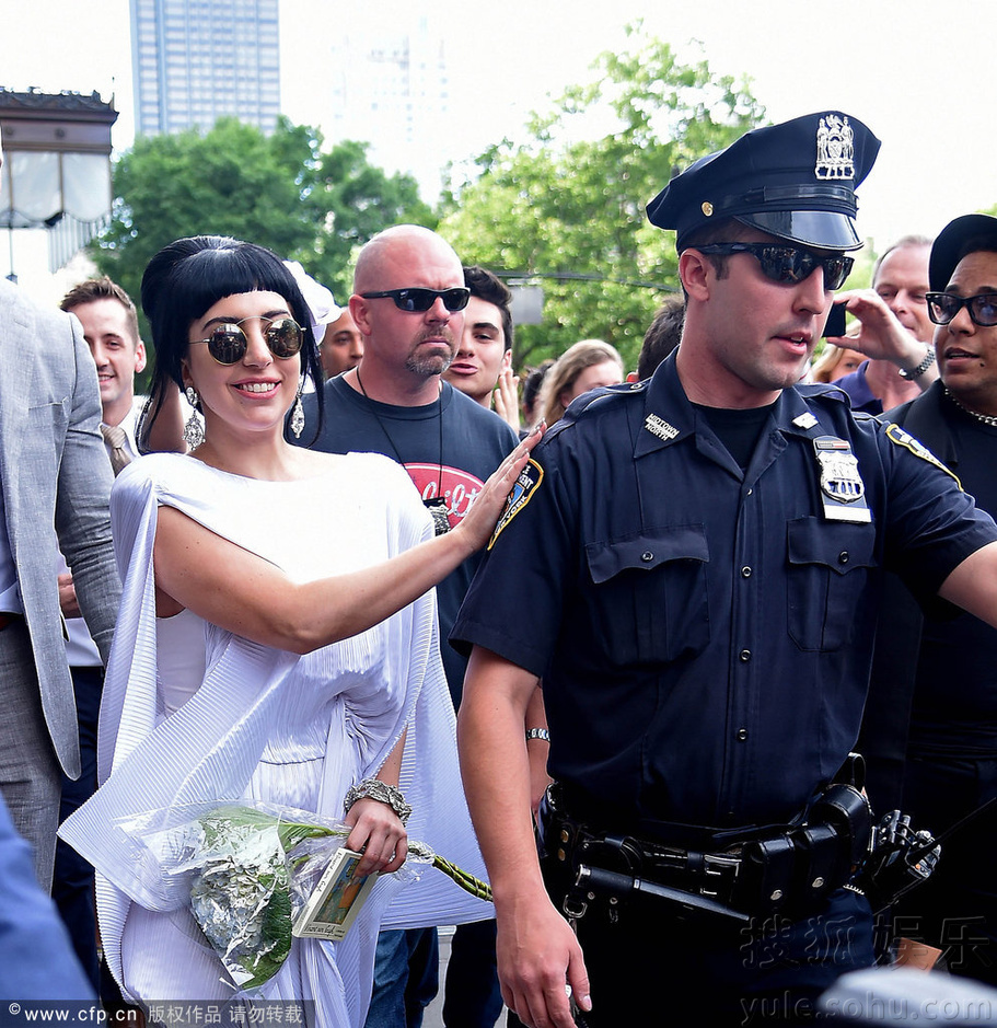 Gaga穿白袍手捧花束扮仙女 拍警察肩膀“调戏”